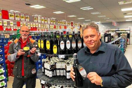 Zwei Mitarbeiter präsentieren Getränkeflaschen im Getränke Star Getränkemarkt in Trier