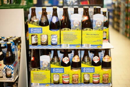 Mehrere 6er-Träger mit Hellem Bier aus Bayern in einem Getränkemarktregal