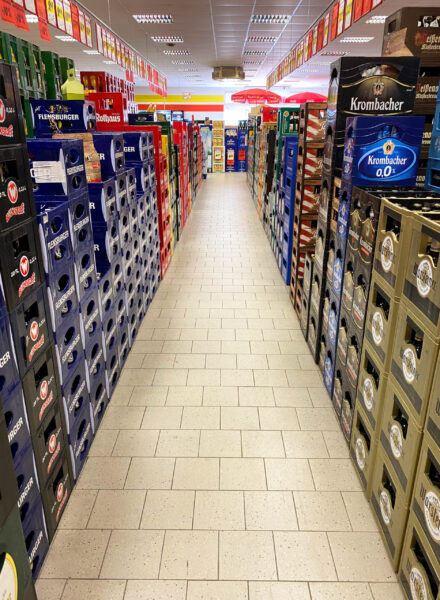 Langer Gang mit gestapelten Bierkisten von Krombacher und Flensburger im Getränke Star Getränkemarkt in Trier