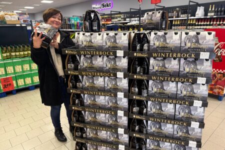 Kundin präsentiert Bitburger Winterbock Bier vor einem Aktionsstapel im Getränke Star Getränkemarkt in Trier