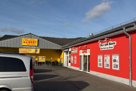 Außenansicht des Getränke Star Getränkemarktes in Trier mit roter Fassade und Werbung „Über 500 Biere – Die Nr.1 in Trier“ neben einem Netto-Markt