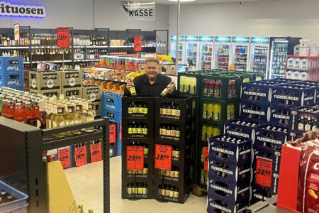 Mitarbeiter im Kassenbereich des Getränke Star Getränkemarkts in Trier zwischen Getränkekisten und Aktionsangeboten