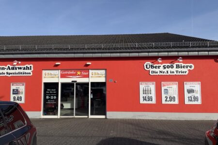 Eingang des Getränke Star Getränkemarktes in Trier mit roter Fassade und Werbung „Über 500 Biere – Die Nr.1 in Trier“