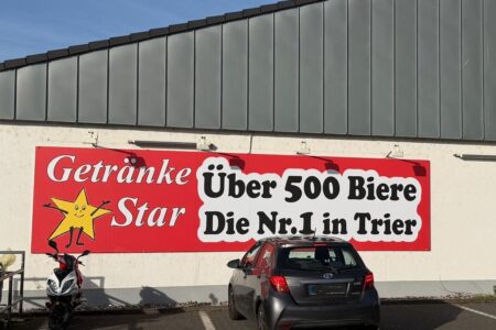 Großes Werbebanner von Getränke Star in Trier mit dem Hinweis „Über 500 Biere – Die Nr. 1 in Trier“ an der Außenwand des Marktes