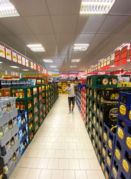 Mitarbeiter steht in einem Gang zwischen gestapelten Getränkekisten im Getränke Star Getränkemarkt Trier