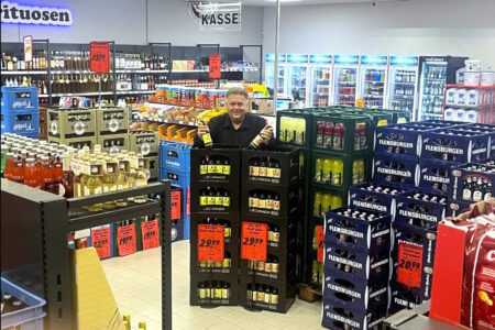 Inhaber des Getränke Star Getränkemarktes in Trier steht zwischen Bierkisten und präsentiert Bierflaschen