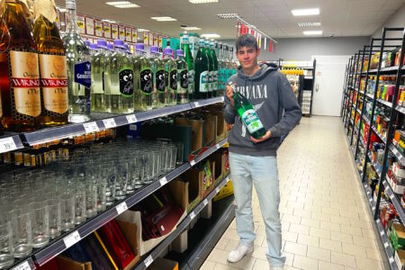 Kunde hält eine Getränkeflasche im Getränke Star Getränkemarkt in Trier zwischen Regalen mit Spirituosen und Gläsern