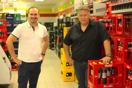 Zwei Mitarbeiter im Getränke Star Getränkemarkt in Trier zwischen Getränkekisten