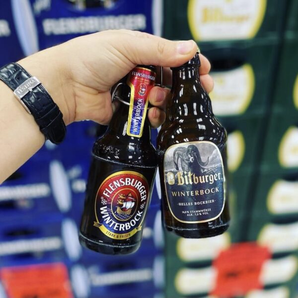 Hand hält Flensburger Winterbock und Bitburger Winterbock Bierflaschen im Getränke Star Getränkemarkt Trier